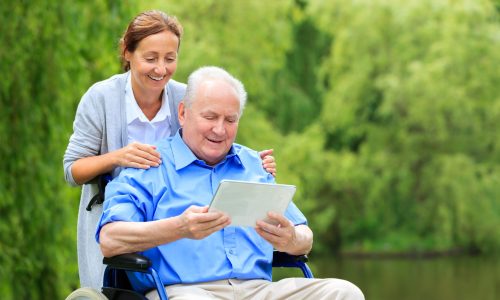 Senior man sitting on a wheelchair with caregiver